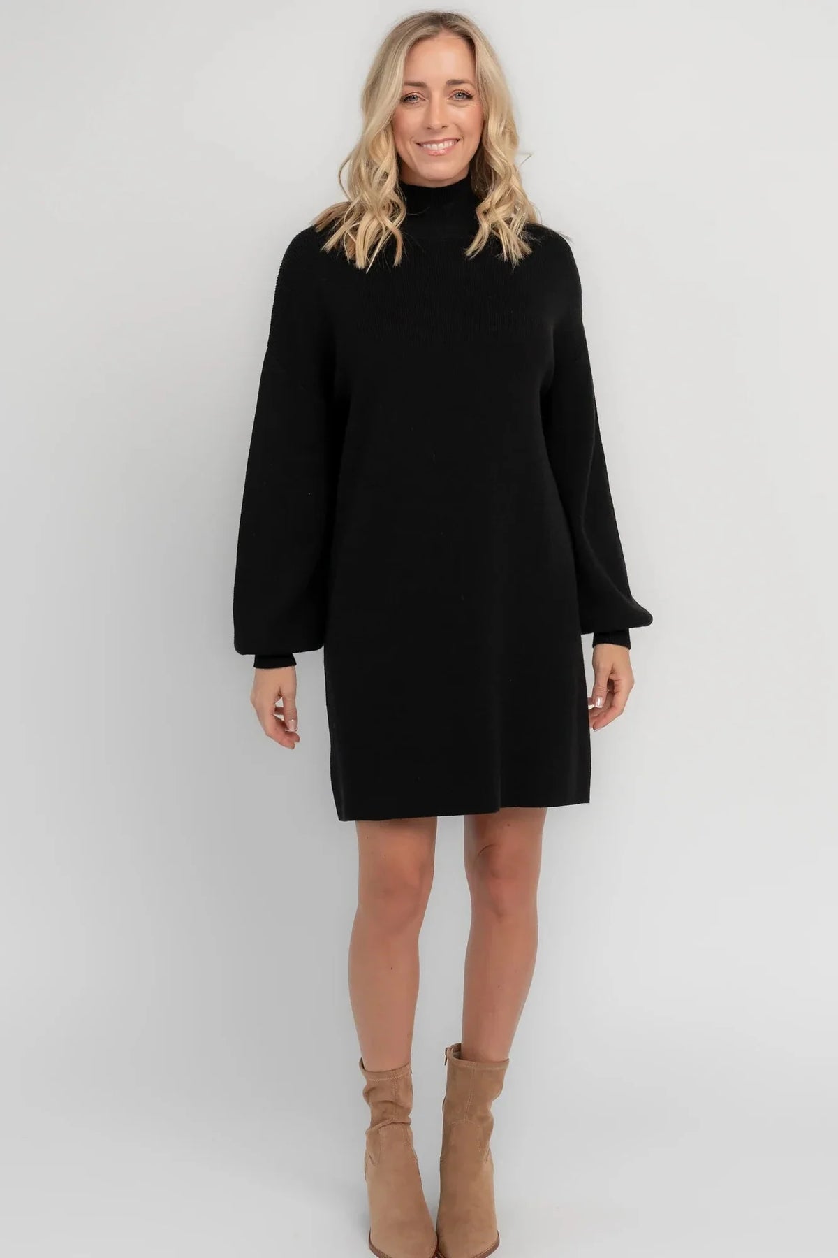 Black knit sweater dress with a mock neckline, long balloon sleeves, dropped shoulders, and a relaxed above-the-knee silhouette.