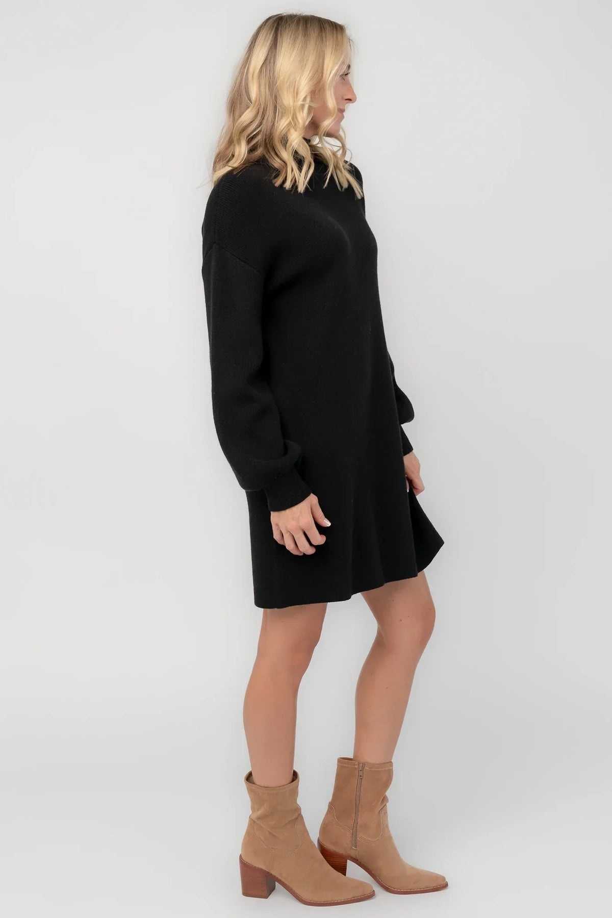 Black knit sweater dress with a mock neckline, long balloon sleeves, dropped shoulders, and a relaxed above-the-knee silhouette.